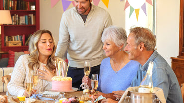Family celebrating a milestone birthday, gathered around a table with a birthday cake.