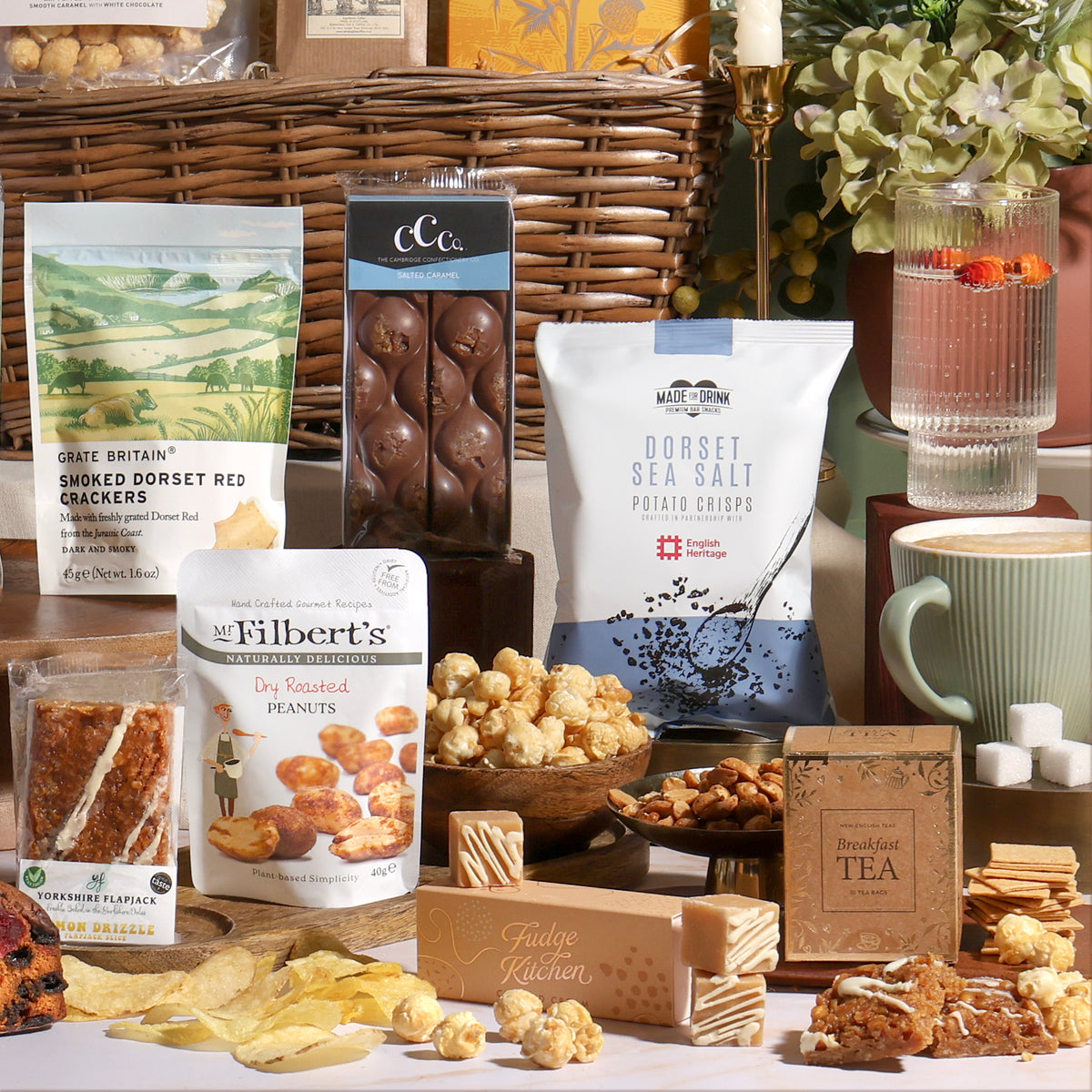 Classic alcohol-free gift basket with the food contents displayed in front, including crackers, nuts, biscuits, chocolate and fudge, arranged around a willow basket.