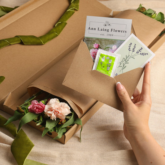 unboxing the seasonal letterbox flower bouquet to reveal flowers and a floral care pack