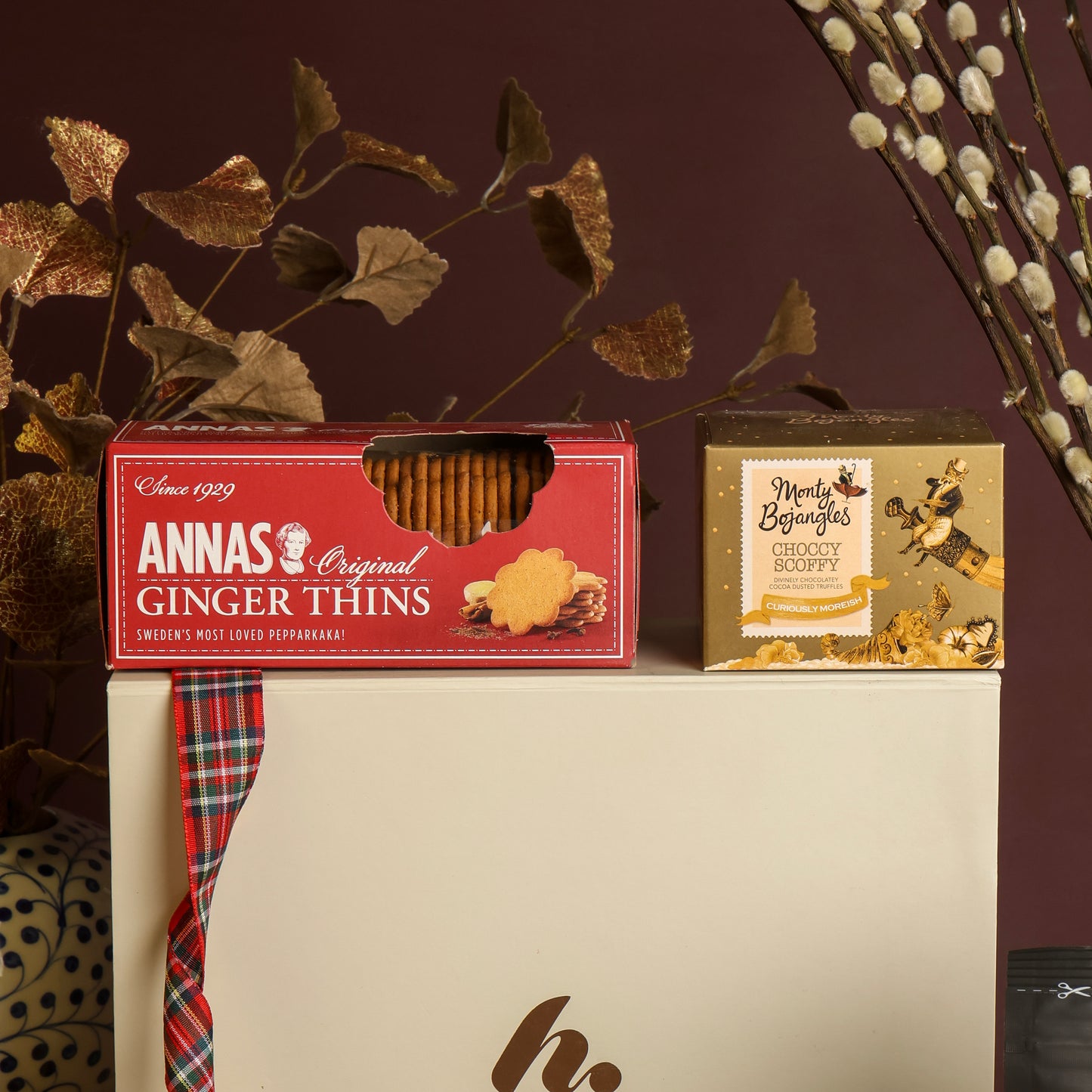Close up of Little Taste of Christmas Hamper displaying Ginger Thins and chocolate truffles, sat on the white branded gift box.