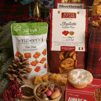 A festive product display featuring Mr Filbert's Tom Yum Mochi Rice Bites, styled with Christmas decorations, pinecones, and mince pies.