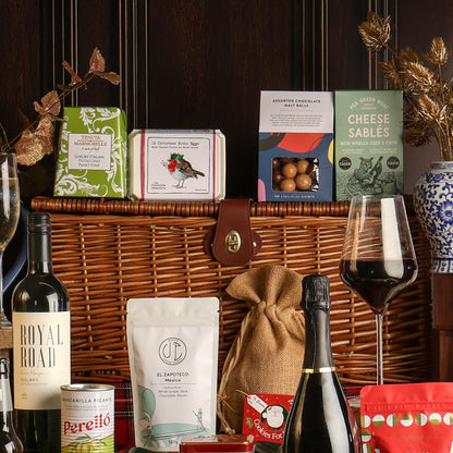 The Luxury Family Sharing Christmas Hamper arranged with its contents surrounding the hamper, styled with a glass of red wine. 