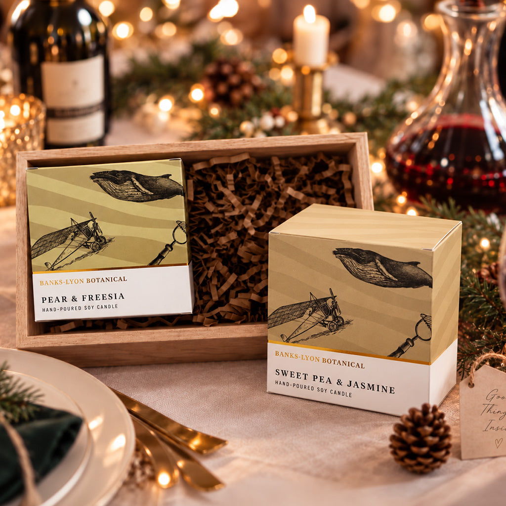 Two boxed soy candles in a Christmas candle gift set, displayed on a festive table setting.
