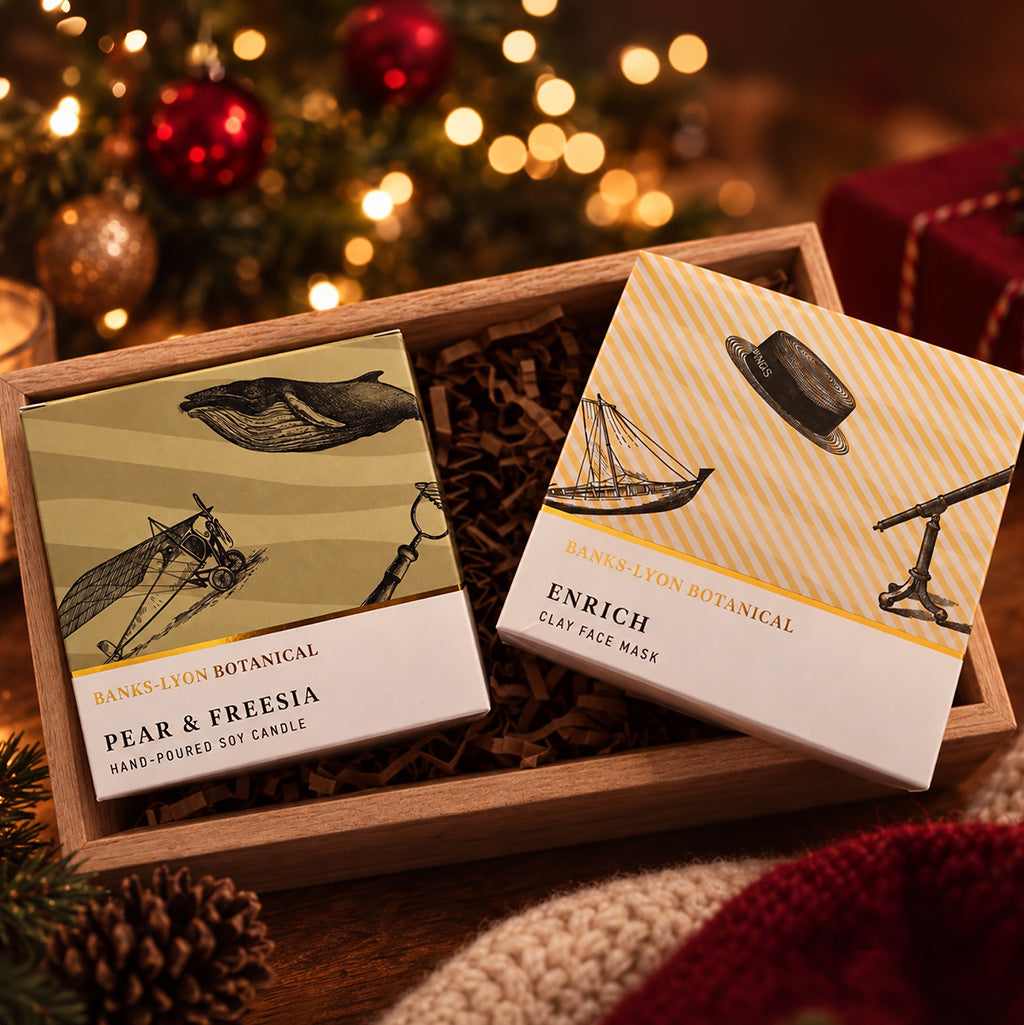 Two Banks-Lyon Botanical products displayed in a wooden gift box, on a warm Christmas themed background.