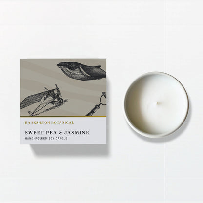 A Banks-Lyon Botanical soy candle box labelled 'Sweet Pea & Jasmine' sits beside a white soy candle, on a white background.