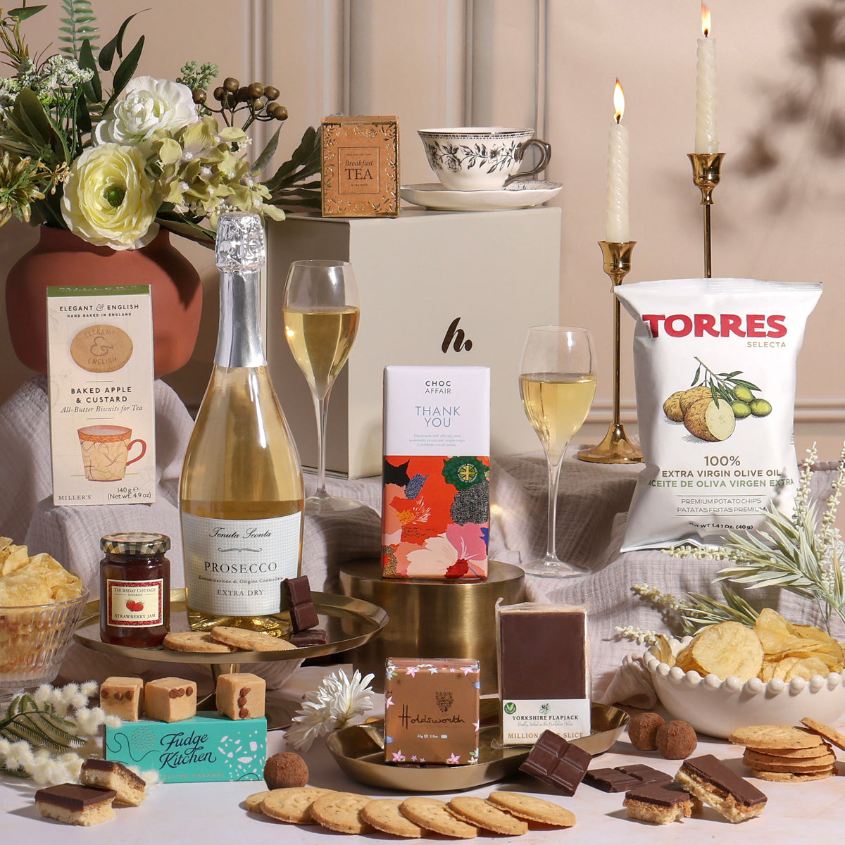 A luxury thank you gift hamper with Prosecco and other treats surrounding a gift box.