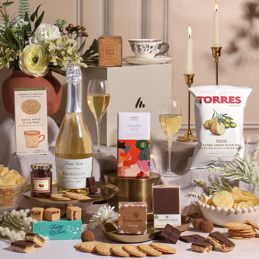 A luxury thank you gift hamper with Prosecco and other treats surrounding a gift box.