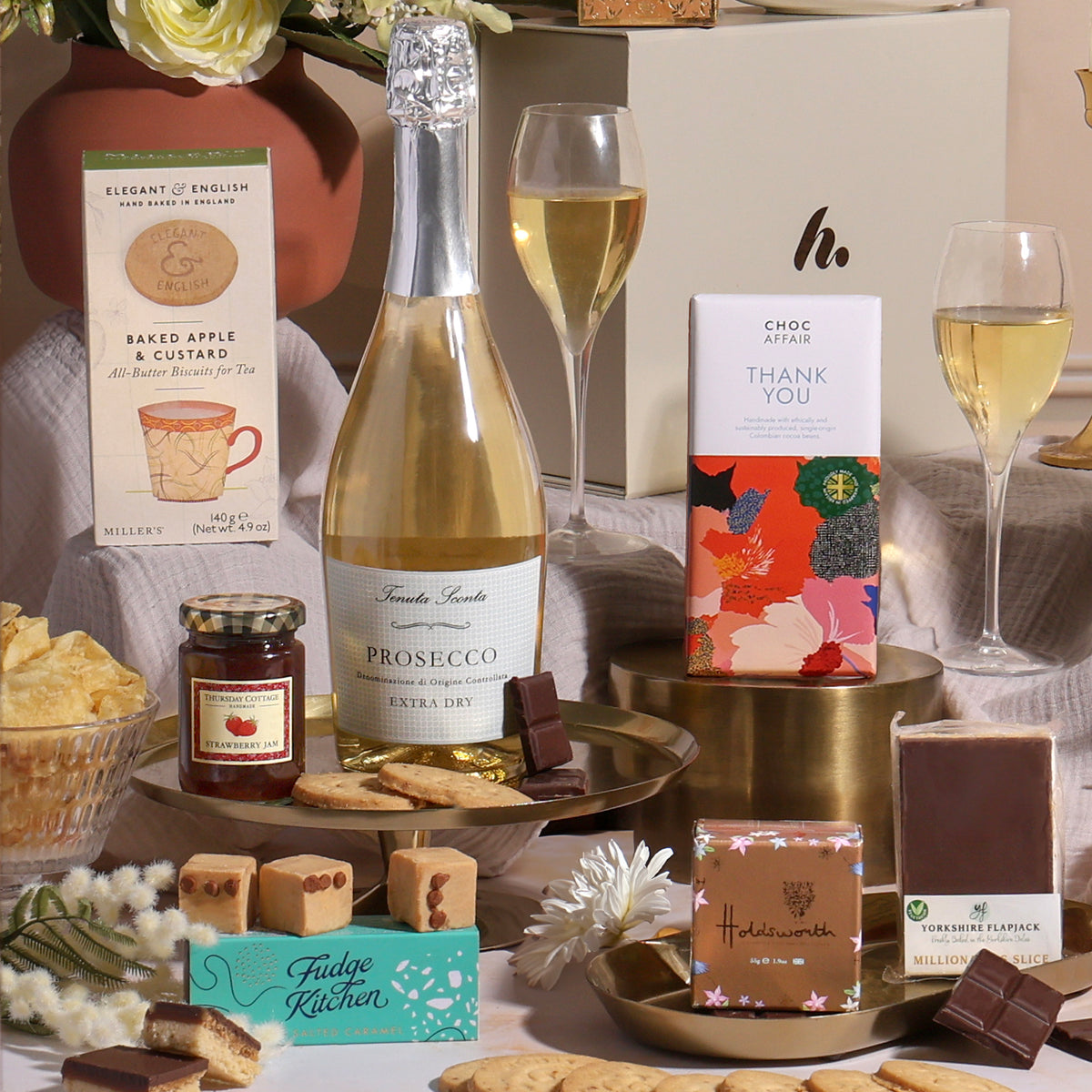 Thank you gift hamper featuring a bottle of Prosecco, assorted chocolates, a jar of jam, and tea.