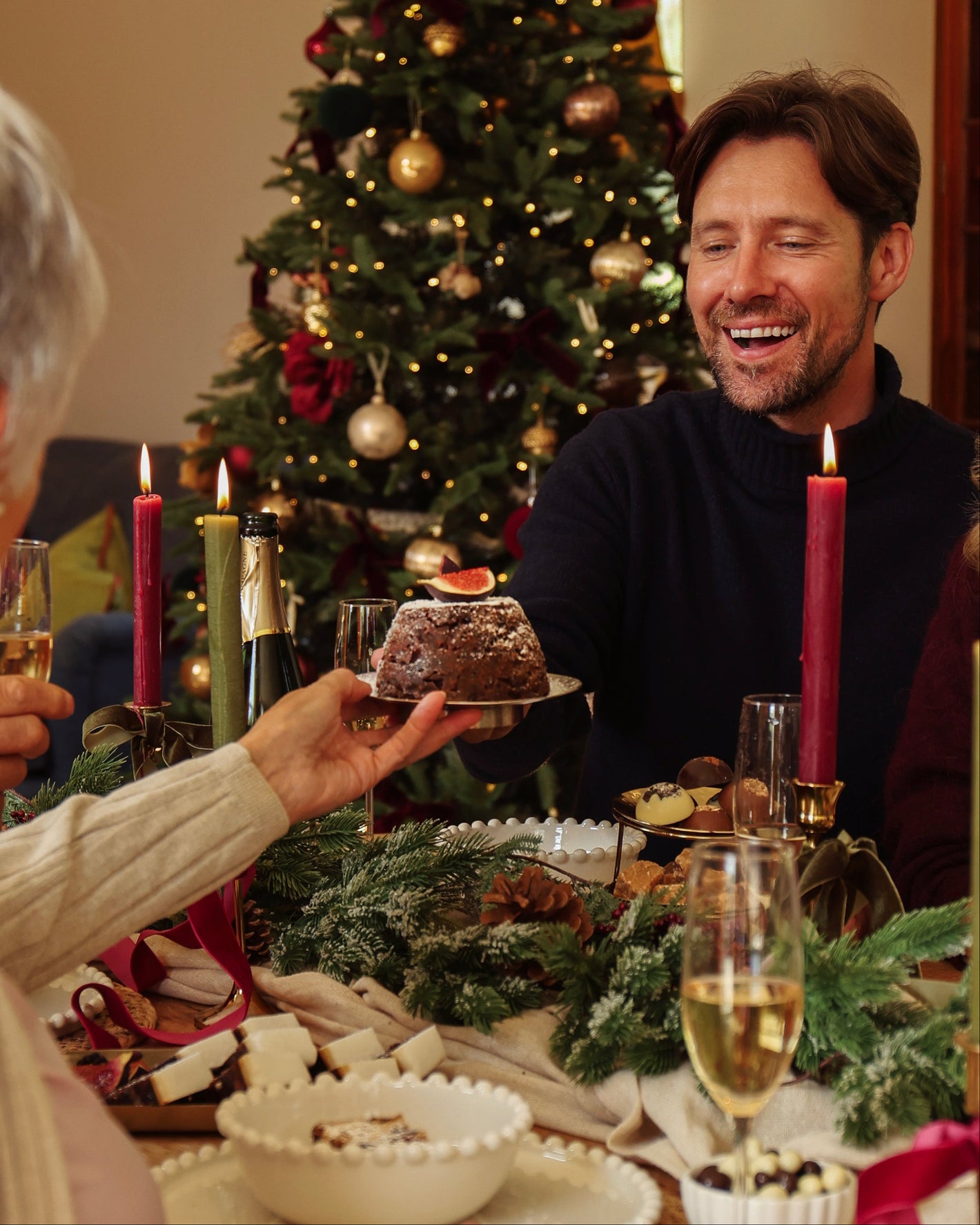 Two people celebrating Christmas with a decorated tree and festive table.