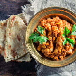 Mamma Spice’s Famous Chickpea Curry in a bowl garnished with coriander and with naan bread on the side