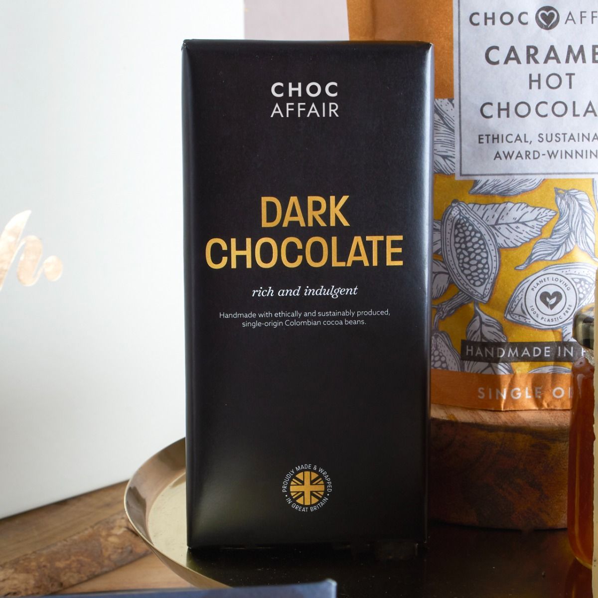 Close up of Choc Affair dark chocolate bar and also caramel hot chocolate pouch