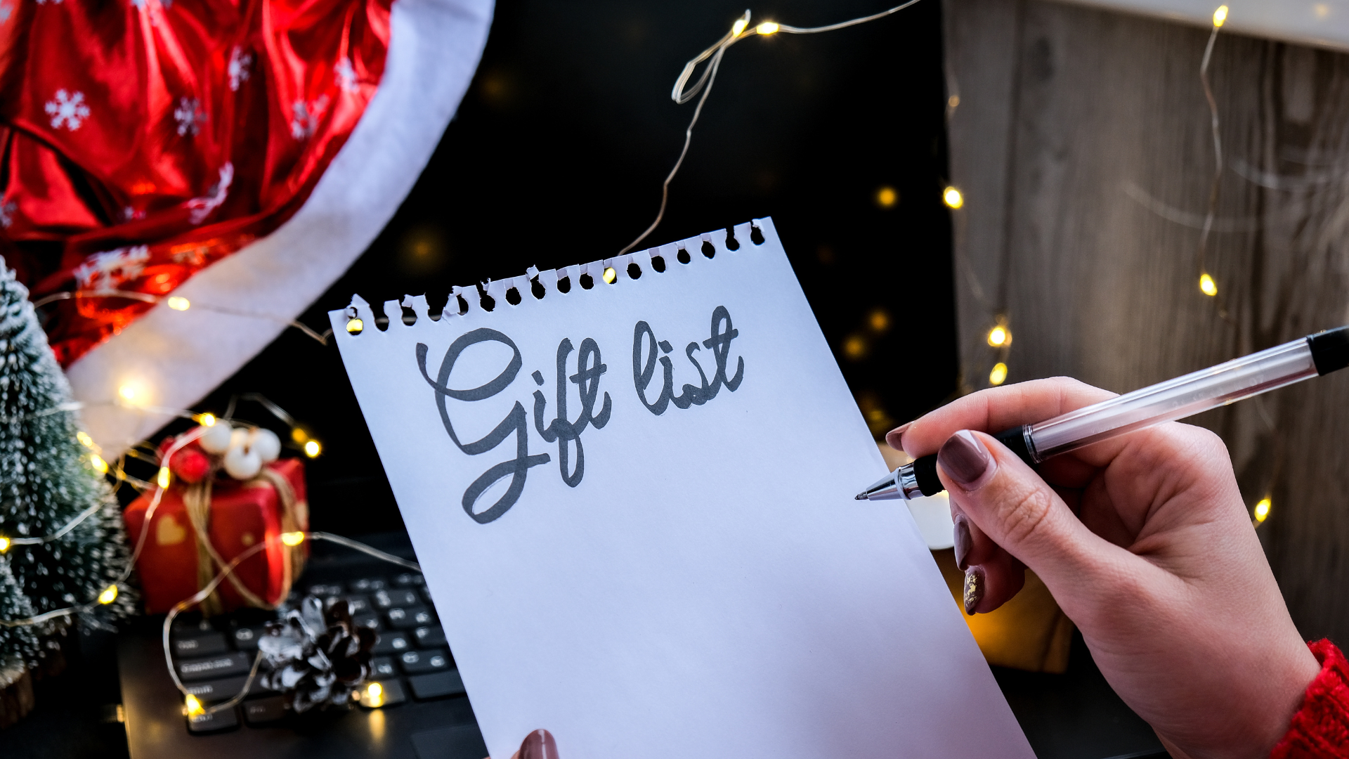 Close up of pen and list saying 'gift list' with Christmas decor in background