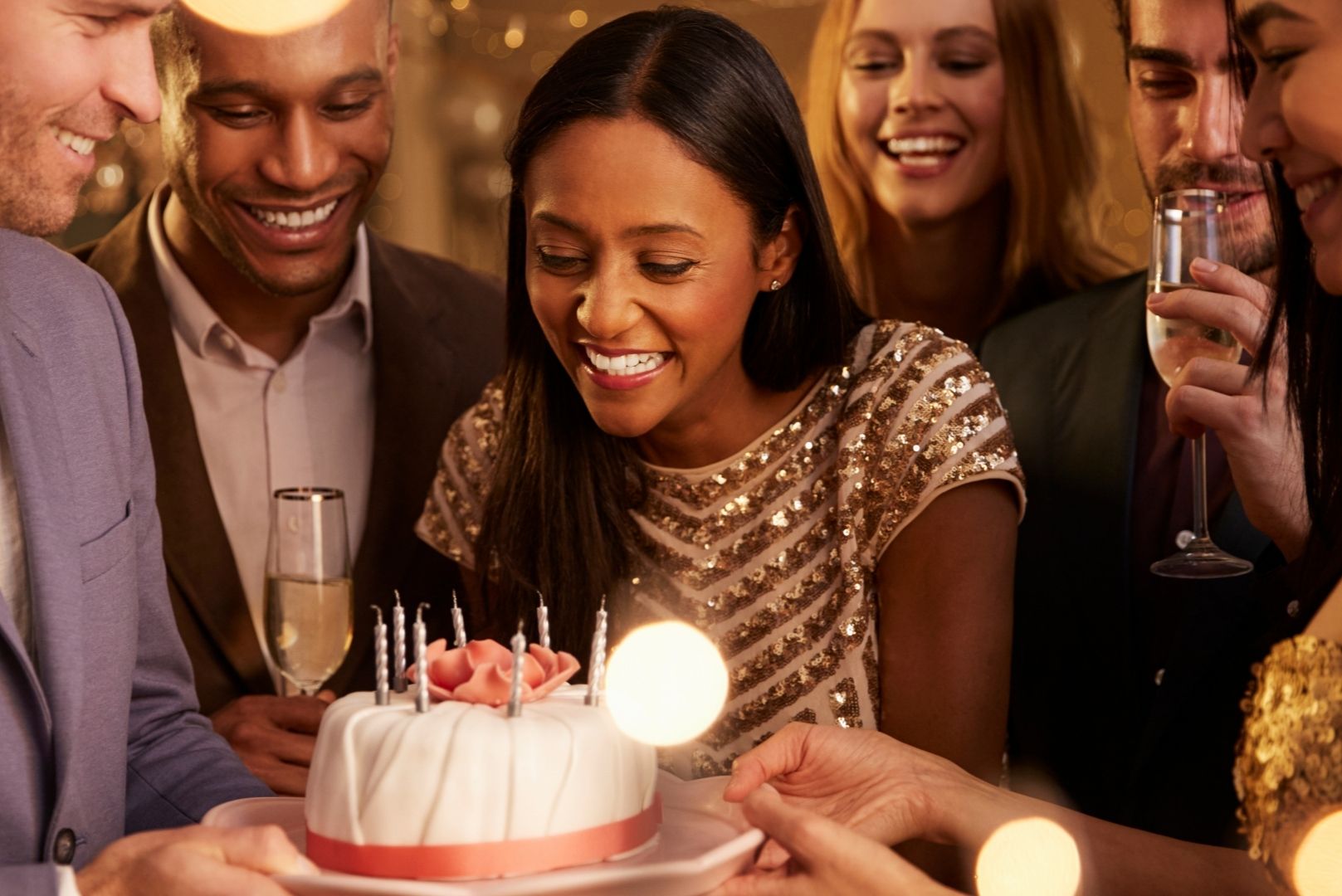 Group of friends presenting a young woman with a birthday cake