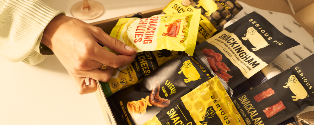 Hand picking from a selection of Serious Pig snacks in bags