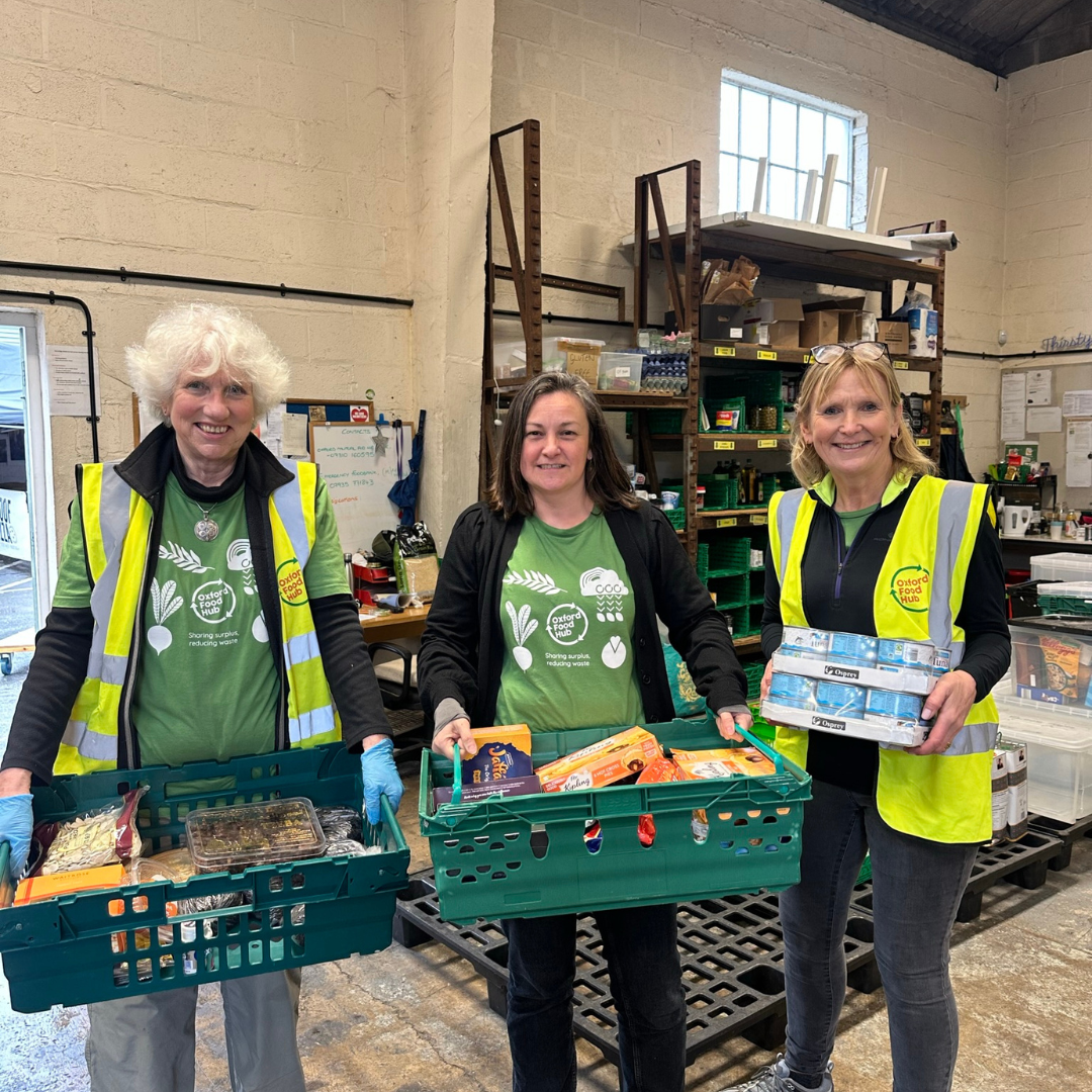 Three volunteers at the Oxford Food Hub holding crates