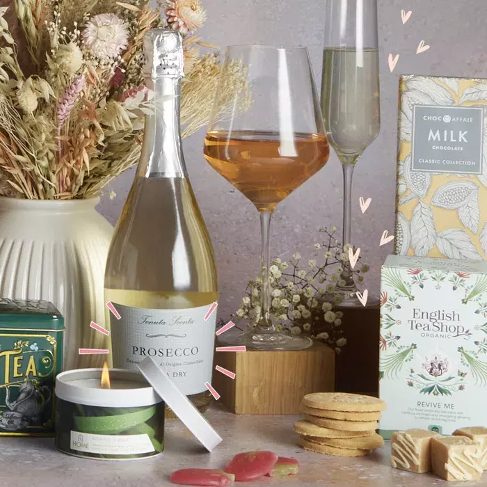 A wine hamper featuring a bottle of luxury rose, chocolate and snacks presented in a wicker basket