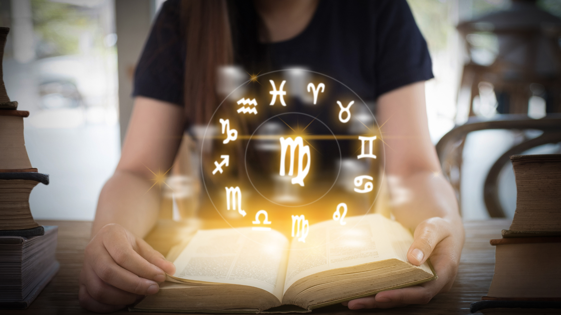 Woman looking a book with symbols of star signs in a circle above