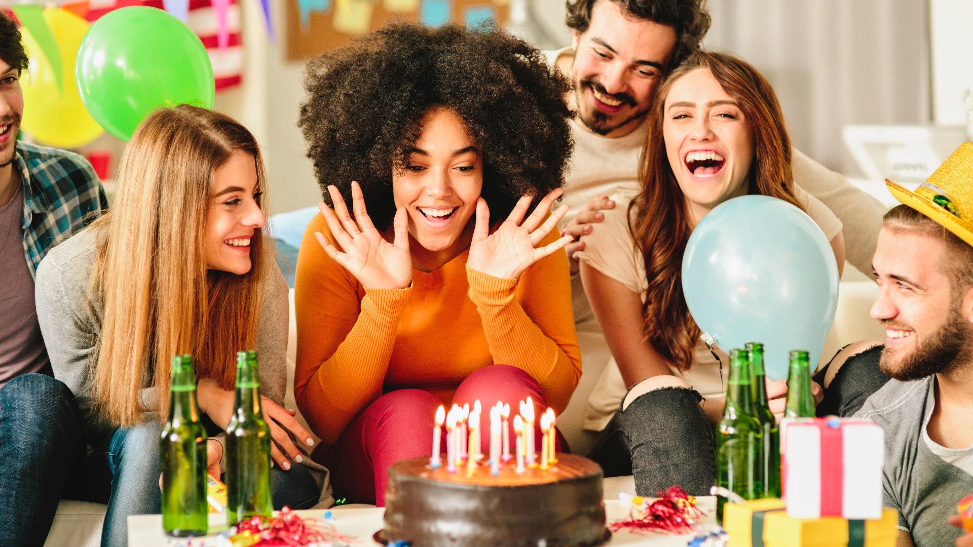 Group of friends around a lady celebrating her birthday looking at a birthday cake