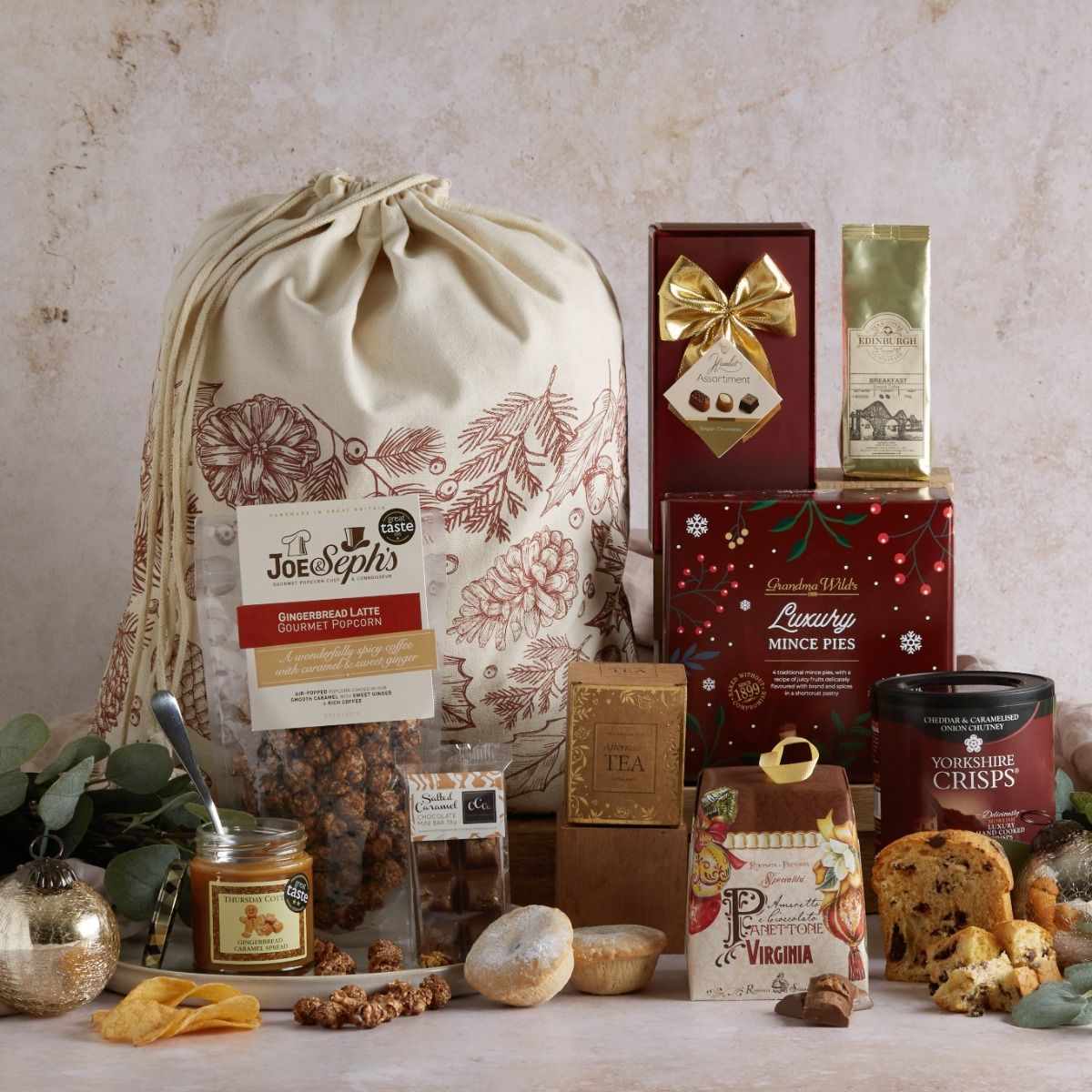 The Festive Favourites Hamper with contents on display and a gold and cream gift bag