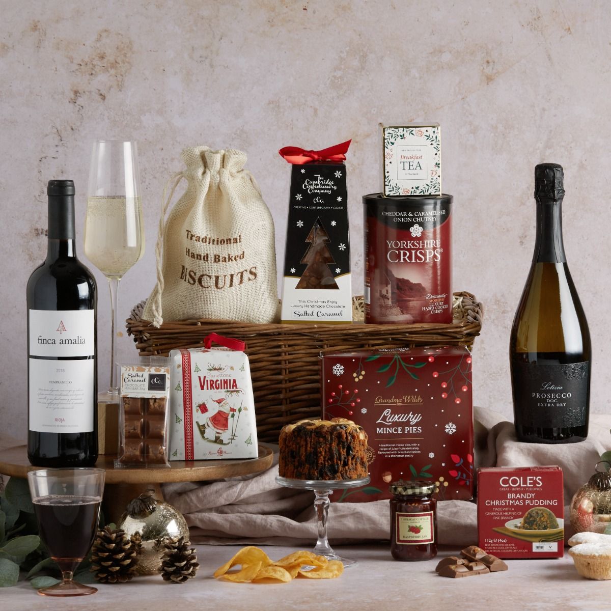Sleigh Bells Hampers with contents on display, a glass of Prosecco and a wicker basket