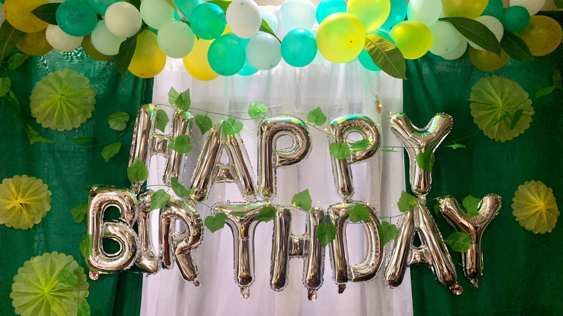 Happy Birthday spelled out in silver balloons with bunting and backdrop