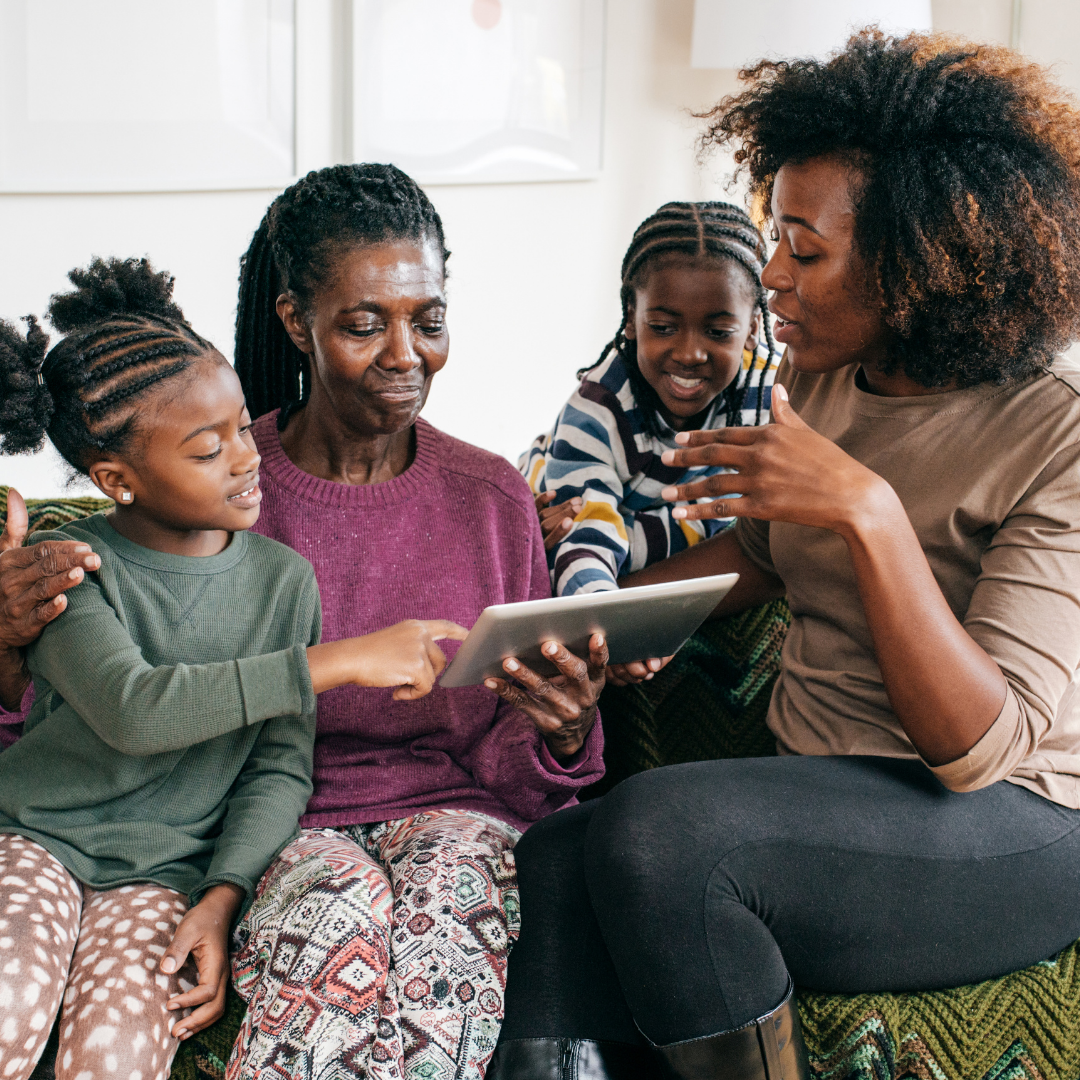 Mum, daughter and her children gathered around a tablet, looking at photos