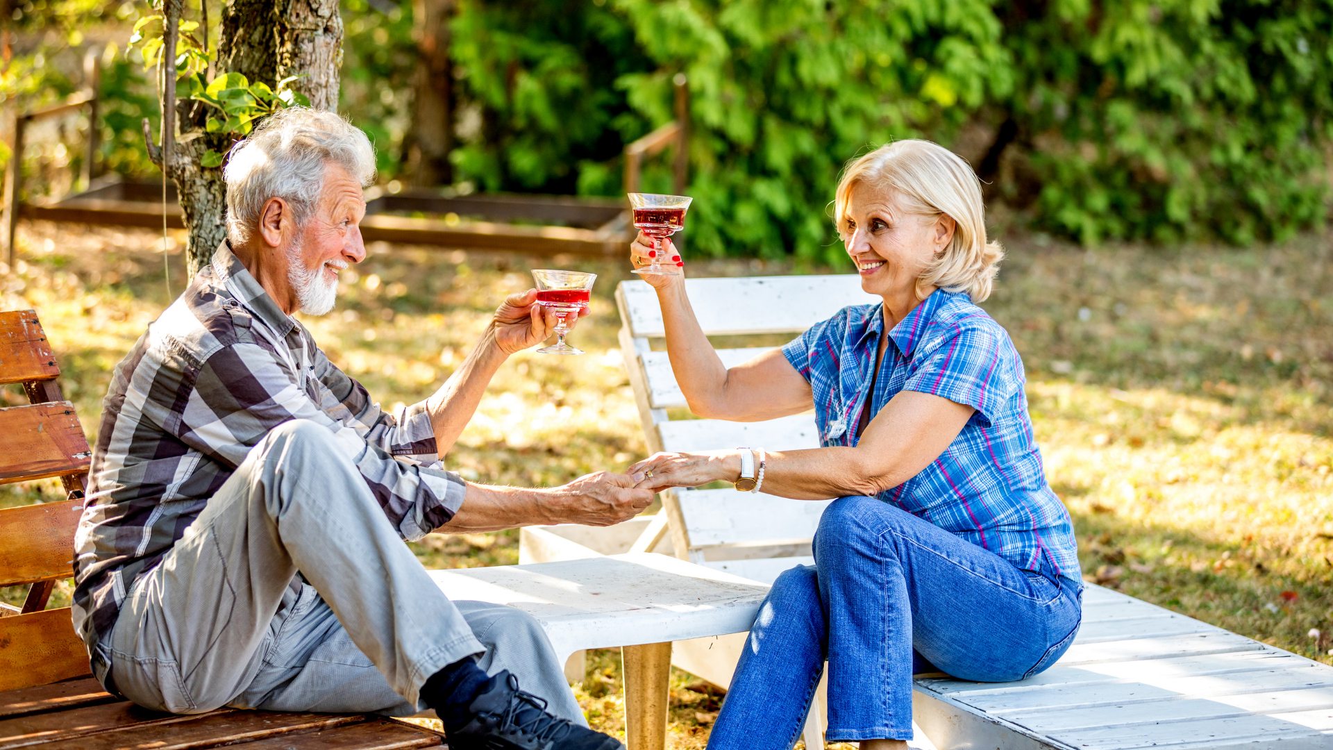 A older couple toasting each other with wine glasses sat outside