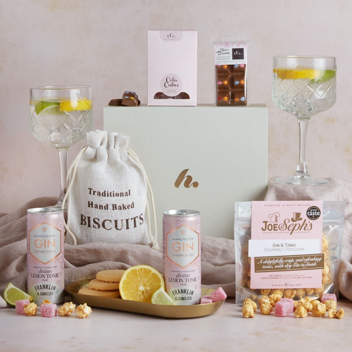 Gin & treats hamper with contents on display, glasses of gin and tonic and a signature cream gift box