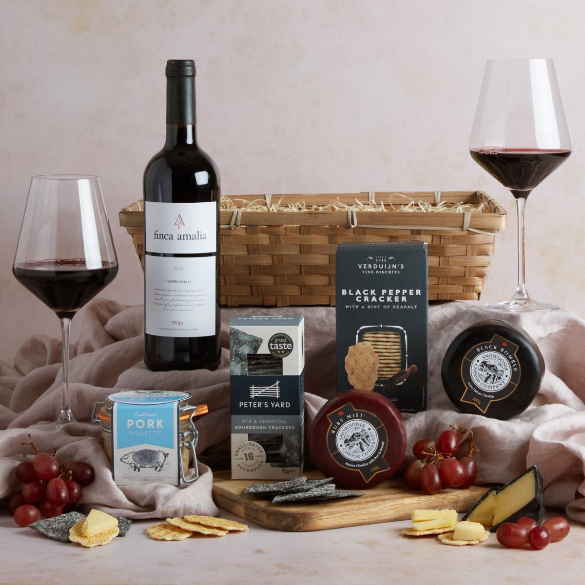 Wine, cheese & rillette hamper with contents on display including a glass of red wine